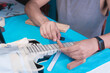 © Alfredo Hernández - Black electric guitar in repair shop with the hands of a guitar luthier fixing it, frets alignment.