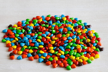 Handful of colorful sweet little glazed multicolored chocolate bonbons candies, m and m's with heart shapes, isolated on white background