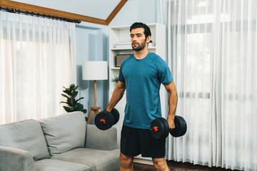 Wall Mural - Athletic body and active sporty man lifting dumbbell weight for effective targeting muscle gain at gaiety home as concept of healthy fit body home workout lifestyle.
