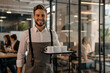 © alfi - Friendly man in apron delivering coffee to office workers with a smile
