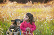 © vvvita - Happy Little girl with a dog walking in the flower field in spring