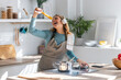 © nenetus - Funny happy young woman listening to music with headphones while cooking raw spaghetti in the kitchen at home