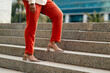 © Meeko Media - Businesswoman Climbing Stairs in Red Pants and Heels, Emphasizing Confidence and Professionalism