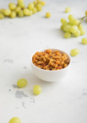 Wall Mural - Green sweet dried raisins on light background with ripe grapes.