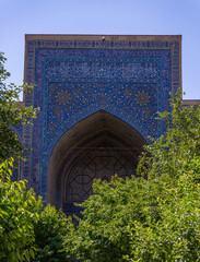 Wall Mural - The blue archway of a building is covered in intricate designs and patterns. The archway is surrounded by trees, which provide a sense of tranquility and serenity