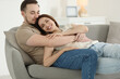 © New Africa - Man hugging his happy girlfriend on sofa at home