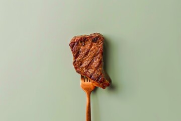 Wall Mural - Grilled steak on a fork against a green background