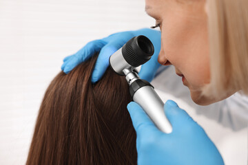 Wall Mural - Trichologist with dermatoscope examining patient`s hair in clinic, closeup