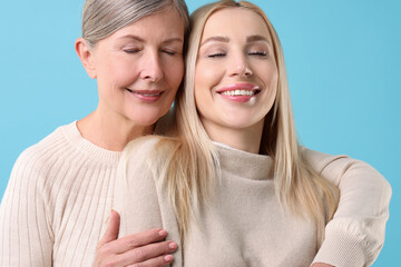 Wall Mural - Family portrait of young woman and her mother on light blue background