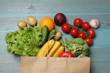 Sticker - Vegan food delivery. Paper bag with different fresh vegetables and fruits on light blue wooden background, flat lay