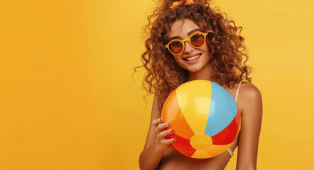 Wall Mural - Happy girl in sunglasses holding beach ball and swimming ring on yellow background with copy space area for text