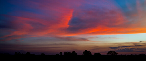 Wall Mural - Panorama Sunlight with dramatic sky on dark background.Vivid sky on dark cloud.Red cloud sky.