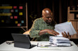 © Wasana - A man is sitting at a desk with a stack of papers in front of him