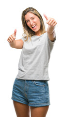 Poster - Young beautiful woman over isolated background approving doing positive gesture with hand, thumbs up smiling and happy for success. Looking at the camera, winner gesture.