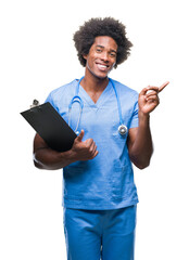 Sticker - Afro american surgeon doctor holding clipboard man over isolated background very happy pointing with hand and finger to the side