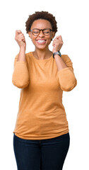 Wall Mural - Young beautiful african american woman wearing glasses over isolated background excited for success with arms raised celebrating victory smiling. Winner concept.