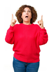 Sticker - Beautiful middle ager senior woman red winter sweater over isolated background amazed and surprised looking up and pointing with fingers and raised arms.