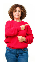 Wall Mural - Beautiful middle ager senior woman red winter sweater over isolated background Pointing with hand finger to the side showing advertisement, serious and calm face