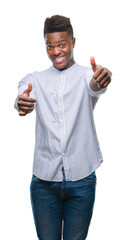 Poster - Young african american man over isolated background approving doing positive gesture with hand, thumbs up smiling and happy for success. Looking at the camera, winner gesture.