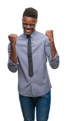 Wall Mural - Young african american business man over isolated background very happy and excited doing winner gesture with arms raised, smiling and screaming for success. Celebration concept.