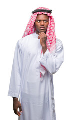 Wall Mural - Young arabic african man wearing traditional keffiyeh over isolated background with hand on chin thinking about question, pensive expression. Smiling with thoughtful face. Doubt concept.