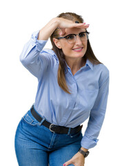 Poster - Beautiful middle age mature business woman wearing glasses over isolated background very happy and smiling looking far away with hand over head. Searching concept.