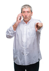 Canvas Print - Handsome senior man talking on smartphone over isolated background pointing with finger to the camera and to you, hand sign, positive and confident gesture from the front