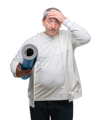 Sticker - Handsome senior man holding yoga mat over isolated background stressed with hand on head, shocked with shame and surprise face, angry and frustrated. Fear and upset for mistake.