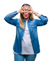 Canvas Print - Young beautiful woman over wearing glasses over isolated background doing ok gesture like binoculars sticking tongue out, eyes looking through fingers. Crazy expression.