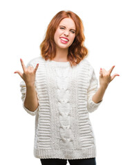 Sticker - Young beautiful woman over isolated background wearing winter sweater shouting with crazy expression doing rock symbol with hands up. Music star. Heavy concept.