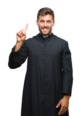 Poster - Young catholic christian priest man over isolated background showing and pointing up with finger number one while smiling confident and happy.