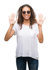 Sticker - Young hispanic woman wearing sunglasses showing and pointing up with fingers number ten while smiling confident and happy.