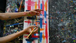 © saltdium - Top view of an artist's hands covered in paint, working on a colorful abstract painting on canvas. Surrounded by paint tubes, brushes, and splattered colors, creative expression and vibrant artistry