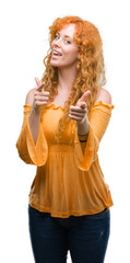 Wall Mural - Young redhead woman pointing fingers to camera with happy and funny face. Good energy and vibes.