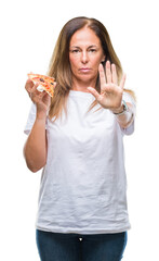 Canvas Print - Middle age hispanic woman eating pizza slice over isolated background with open hand doing stop sign with serious and confident expression, defense gesture