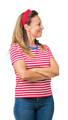 Wall Mural - Beautiful middle age woman wearing casual stripes t-shirt over isolated background smiling looking to the side with arms crossed convinced and confident