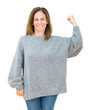 © Krakenimages.com - Beautiful middle age woman wearing winter sweater over isolated background Strong person showing arm muscle, confident and proud of power