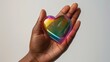 © Nadin Faust - close-up of african american woman's hand holding a rainbow iridescent heart, isolated on a white background with studio lighting for valentine's day concept