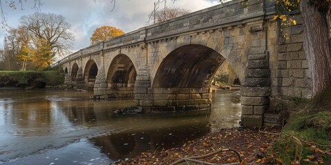 Wall Mural - A stone bridge spanning a river with lush greenery in the background, perfect for landscape or nature scenes