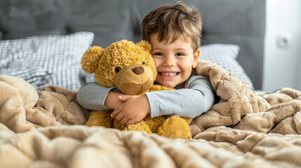 Wall Mural - A young boy is hugging a teddy bear while lying in bed