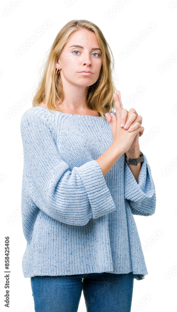 Beautiful young woman wearing blue sweater over isolated background Holding symbolic gun with hand gesture, playing killing shooting weapons, angry face