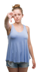 Wall Mural - Young blonde woman looking unhappy and angry showing rejection and negative with thumbs down gesture. Bad expression.