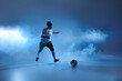 © LIGHTFIELD STUDIOS - Female athlete in white jersey and green shorts dribbles soccer ball under blue sky.