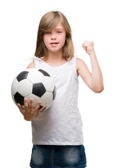 Sticker - Young blonde toddler holding football ball annoyed and frustrated shouting with anger, crazy and yelling with raised hand, anger concept