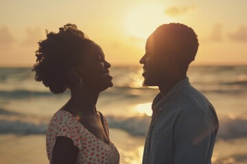 Wall Mural - Happy African couple chatting on beach at sunset.