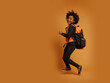 © Alex - Run out cheerful black african american boy, afro haircut, backpack, orange isolated background
