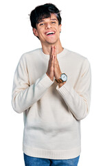 Poster - Handsome hipster young man wearing casual winter sweater praying with hands together asking for forgiveness smiling confident.