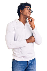 Sticker - Handsome african american man with afro hair wearing casual clothes and glasses with hand on chin thinking about question, pensive expression. smiling with thoughtful face. doubt concept.