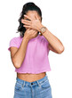 © Krakenimages.com - Hispanic teenager girl with dental braces wearing casual clothes covering eyes and mouth with hands, surprised and shocked. hiding emotion
