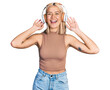 © Krakenimages.com - Beautiful young blonde woman listening to music using headphones smiling and laughing hard out loud because funny crazy joke.